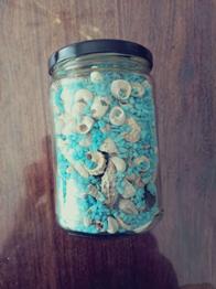 Ein Glas mit Dekosand und Muscheln